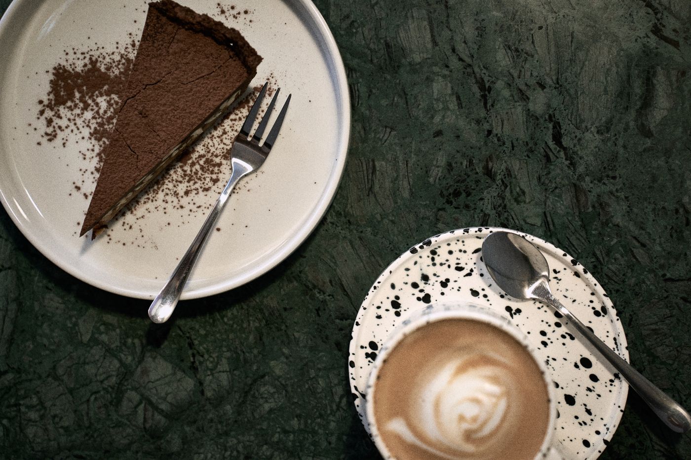 Kawałek czekoladowego ciasta i latte na zielonym marmurze