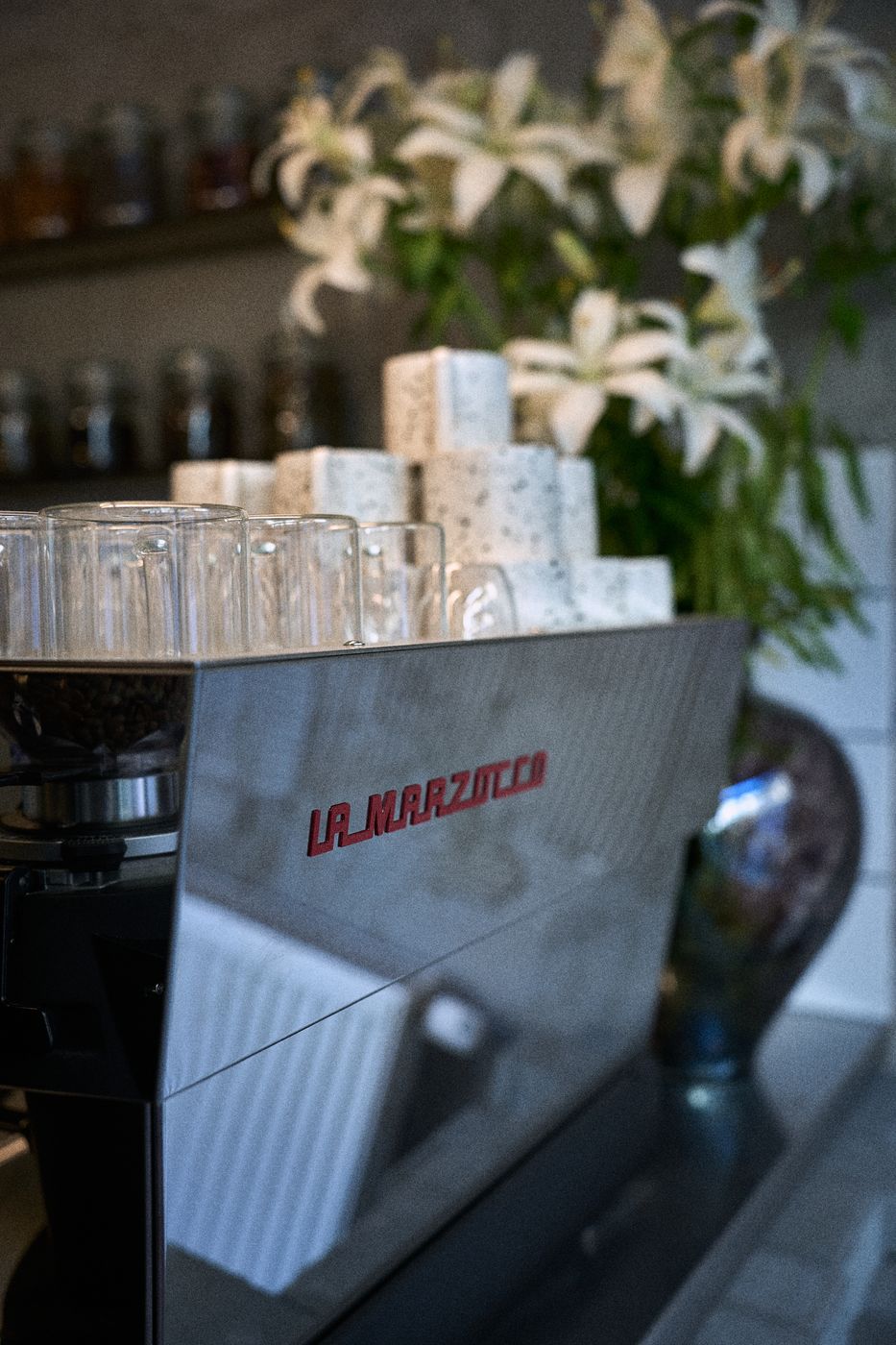 Ekspres La Marzocco i białe lilie za barem